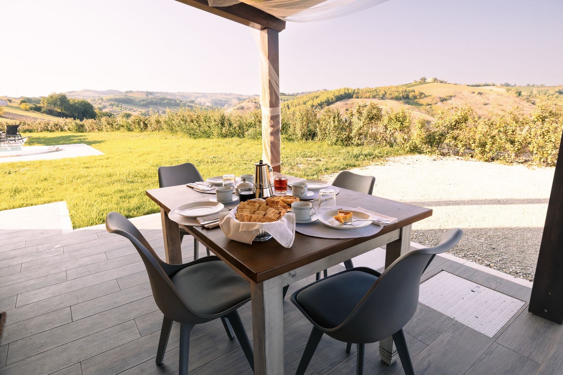 Tavolo della colazione sotto il pergolato con vista sulle colline