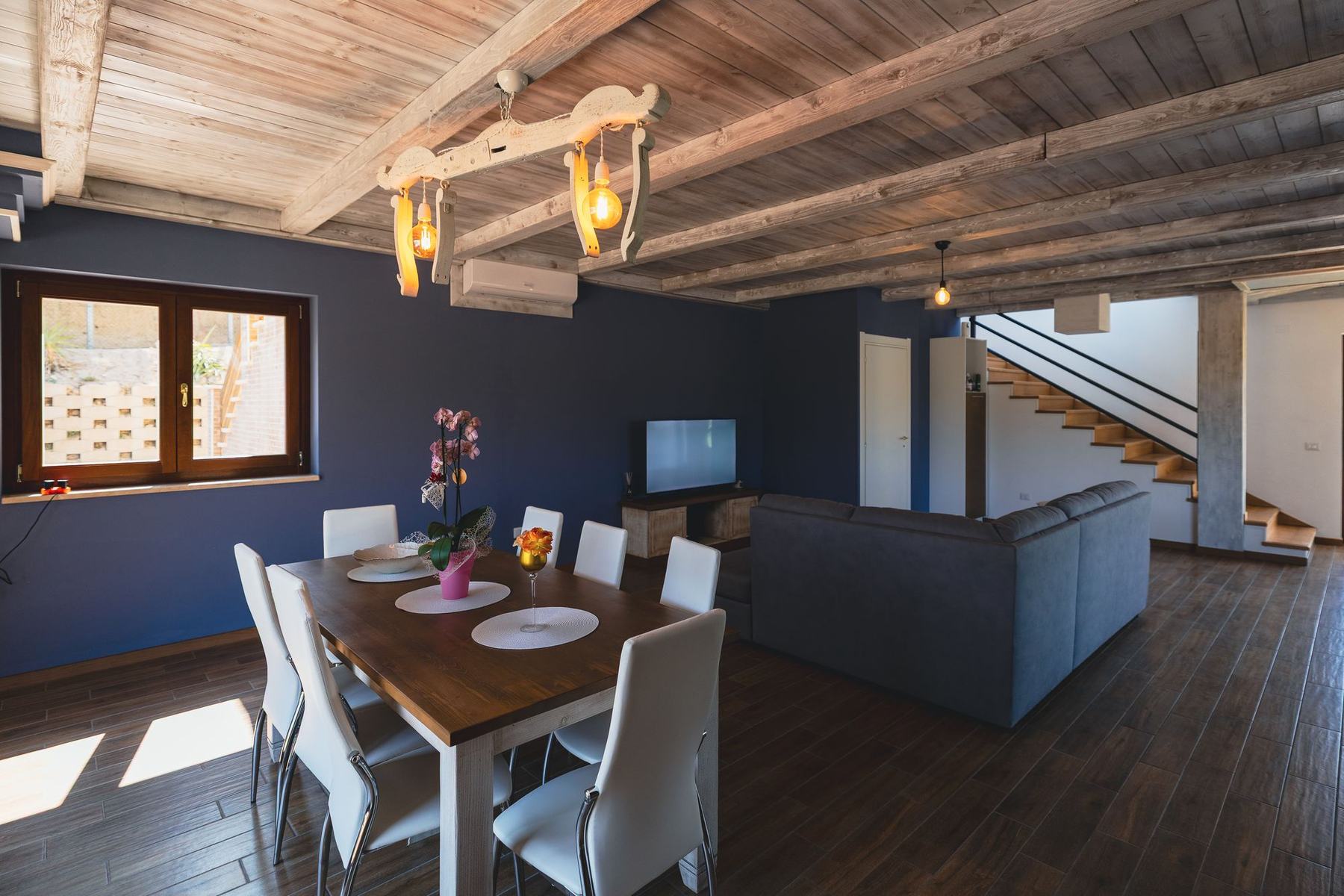 Il salotto con travi in legno, tavolo da pranzo e divano