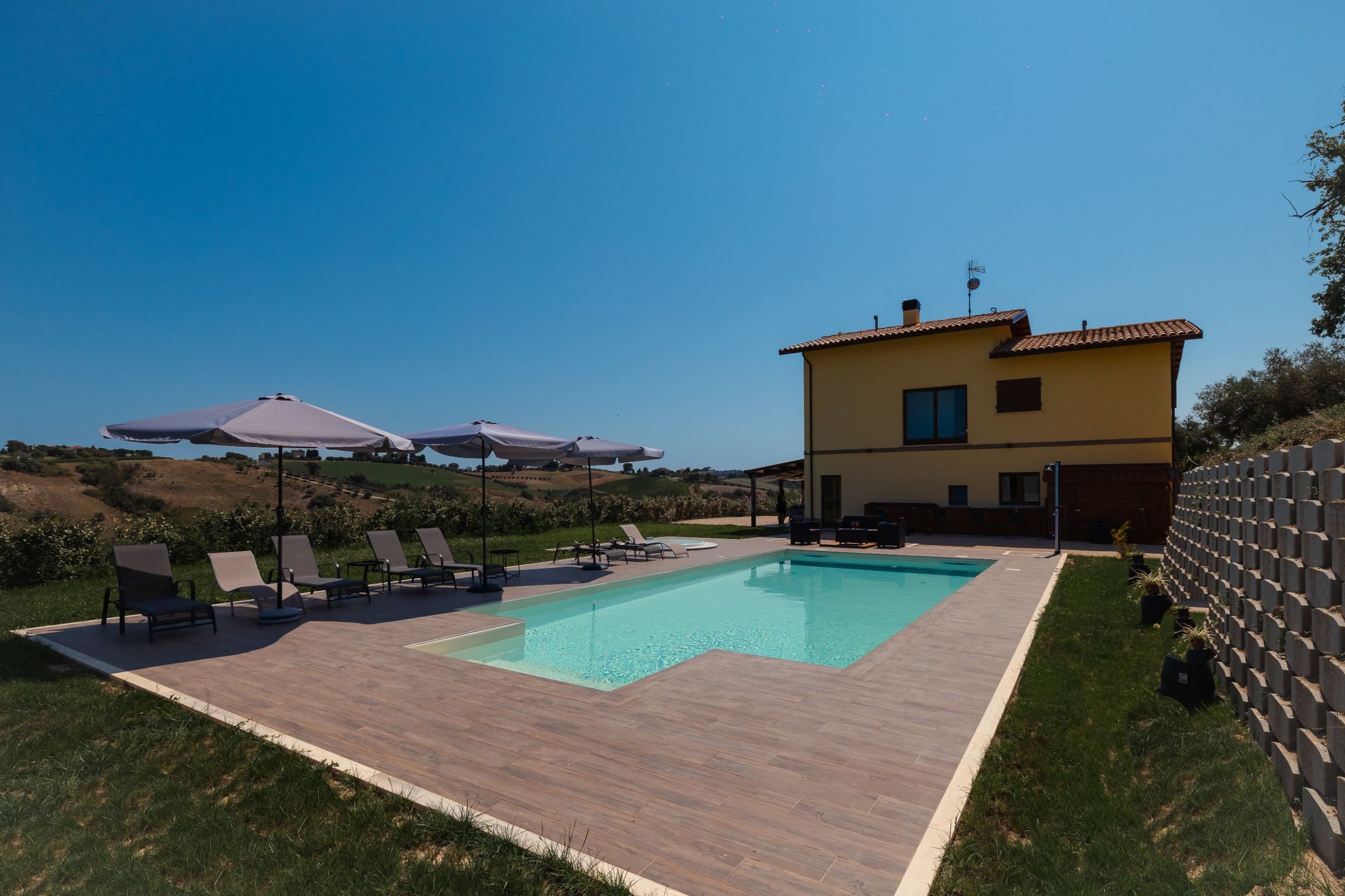 La piscina con scalinata e la jacuzzi sul deck, davanti alle colline